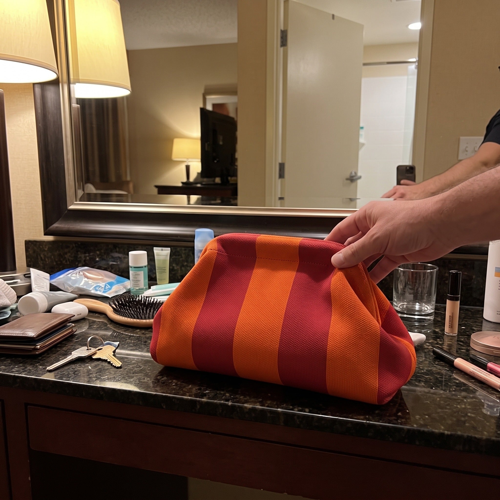Red and orange Pop Pouch on a hotel bathroom counter